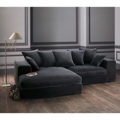 a black couch sitting on top of a hard wood floor next to a lamp and wall