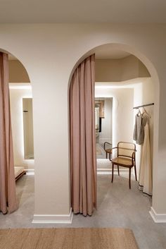 an arched doorway leads into a bedroom with beige curtains