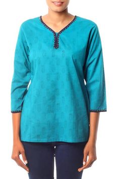 Cool cotton in a rich turquoise tone inspires Isha Jain. She designs this charming tunic with paisley motifs created by hand with the block print technique. Dark blue piping and golden beads complete the charming top. It slips over the head and slits on both sides assure an easy fit. Casual Turquoise Cotton Blouse, Festive Green Cotton Tunic, Traditional Green Cotton Tunic, Blue Cotton Straight Kurta Tops, Fitted Blue Block Print Tops, Fitted Blue Top With Block Print, Fitted Cotton V-neck Tunic, Green Fitted Straight Kurta Top, Casual Green Straight Kurta Top