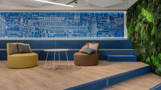 an office with blue walls and green plants on the wall, two chairs in front of a coffee table