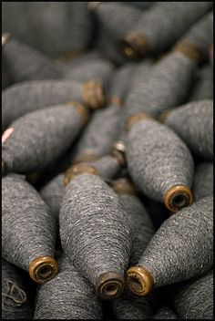 many gray and gold spools of thread are stacked together on top of each other