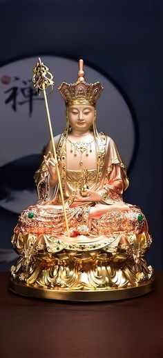 a golden buddha statue sitting on top of a wooden table