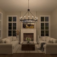 a living room filled with furniture and a fire place under a chandelier over a fireplace