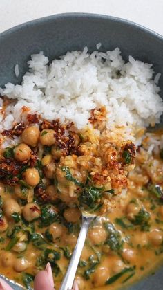 a bowl filled with rice, beans and spinach next to a spoon in it