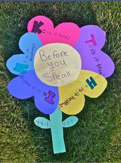 a bunch of paper flowers with words written on them sitting in the middle of grass