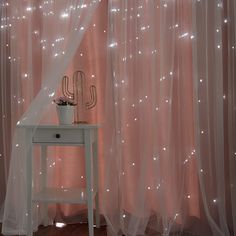 a white table with a cactus on it next to a window covered in sheer curtains