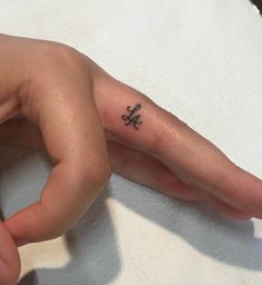 a person's hand with a small tattoo on the middle finger and an anchor in the middle