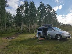 an rv parked in the middle of a grassy field with trees and grass around it