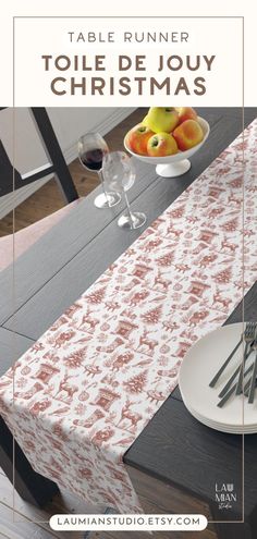 a table runner with red and white designs on it, next to a bowl of fruit