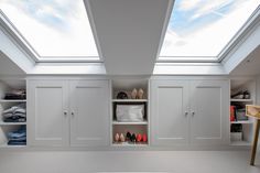 a white closet with skylights and shoes on the shelves in it's center