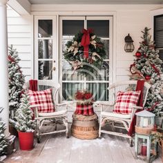 a porch decorated for christmas with red and white plaid pillows, wreaths and evergreen trees