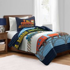 a child's bed with a train comforter and pillows