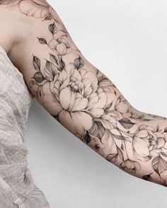 a woman's arm with flowers and leaves tattooed on the arm, in black and white