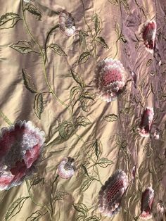 the fabric is covered with pink flowers and green leaves on gold colored background, closeup