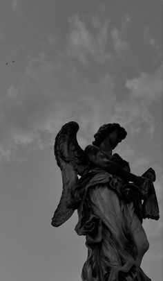 an angel statue in front of a cloudy sky