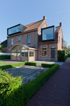 a large brick building with lots of windows on the front and side of it, surrounded by greenery