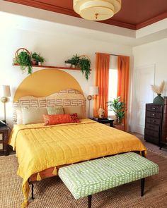 a large bed sitting in a bedroom next to a dresser and window with potted plants on top of it