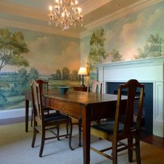 a dining room table with chairs and a fireplace in front of a painting on the wall