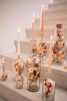 candles and vases with flowers in them on the stairs