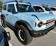 a light blue truck parked in a parking lot next to other cars and trucks with writing on the windows