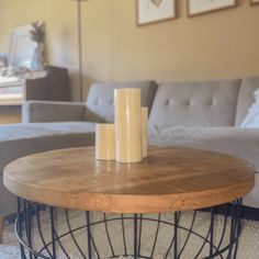 two candles sitting on top of a wooden table in front of a gray sectional couch