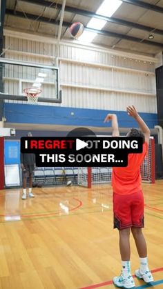 a young man standing on top of a basketball court with his arms in the air