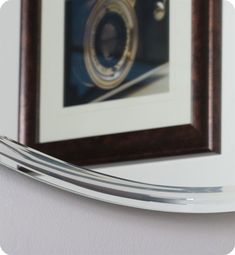 a close up of a mirror on a wall with a camera in the background and a framed photograph behind it