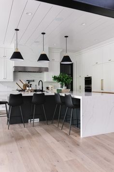 a large kitchen with white cabinets and black chairs in the center island, along with marble counter tops