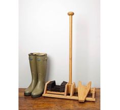 a pair of rubber boots and an umbrella stand on a wooden floor next to a boot rack