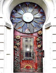 a red door with a stained glass window and sunflowers on the front panel