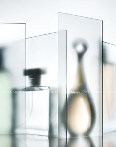 three glass containers with perfume bottles in them