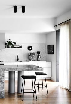 a kitchen with marble counter tops and stools next to an island in the middle