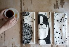 three napkins with black and white designs on them, one has a dog in the middle