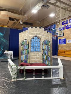 a castle made out of cardboard sitting on top of a stage in a building with blue curtains