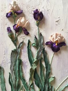 three purple and white flowers sitting on top of a wall