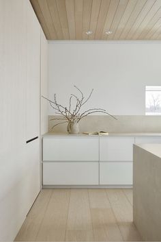 a kitchen with white cabinets and wood flooring in the middle of an empty room