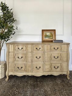 a white dresser with drawers and a potted plant next to it