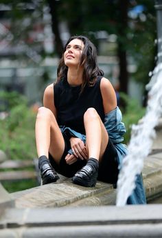 a woman sitting on the edge of a fountain