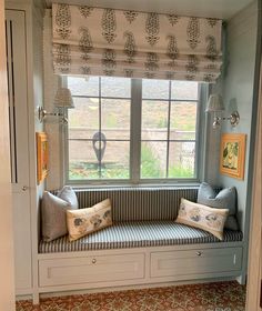 a window seat in the corner of a room with two pillows on top of it