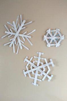 three snowflakes made out of popsicle sticks are on the wall next to each other