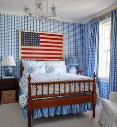 a bedroom with blue and white checkered wallpaper, a large american flag on the headboard