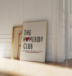 a white framed sign sitting on top of a wooden floor next to an open door