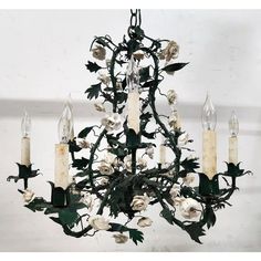 a chandelier with white flowers and candles hanging from it's center piece