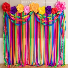 colorful streamers and flowers are hanging on the wall behind a curtain made out of ribbons