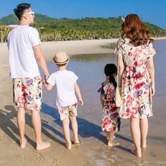 a man and two children are standing on the beach looking out at the water with palm trees in the background