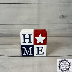 a red, white and blue block with the word home on it sitting next to a piece of paper