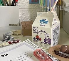 a carton of milk sitting on top of a desk next to pens and pencils