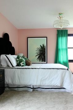 a bedroom with pink walls and white carpeted flooring, black headboard on the bed