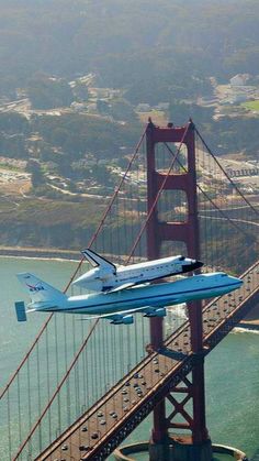 an airplane flying over the golden gate bridge with a space shuttle on it's back