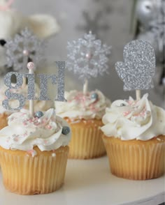 three cupcakes with frosting and decorations on top are sitting on a table